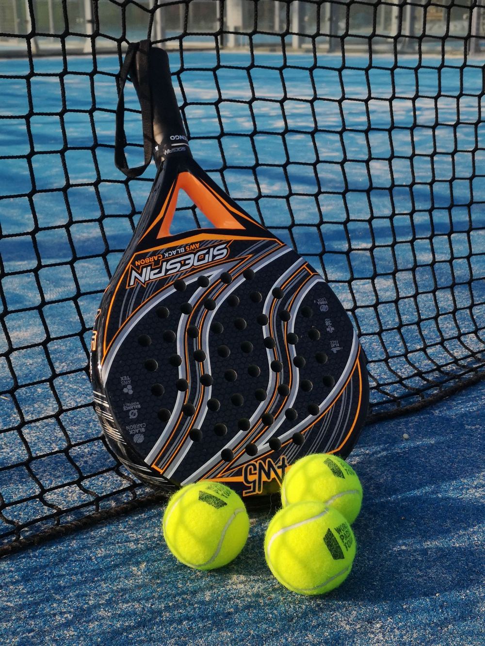 Raquette et balles de padel contre le filet